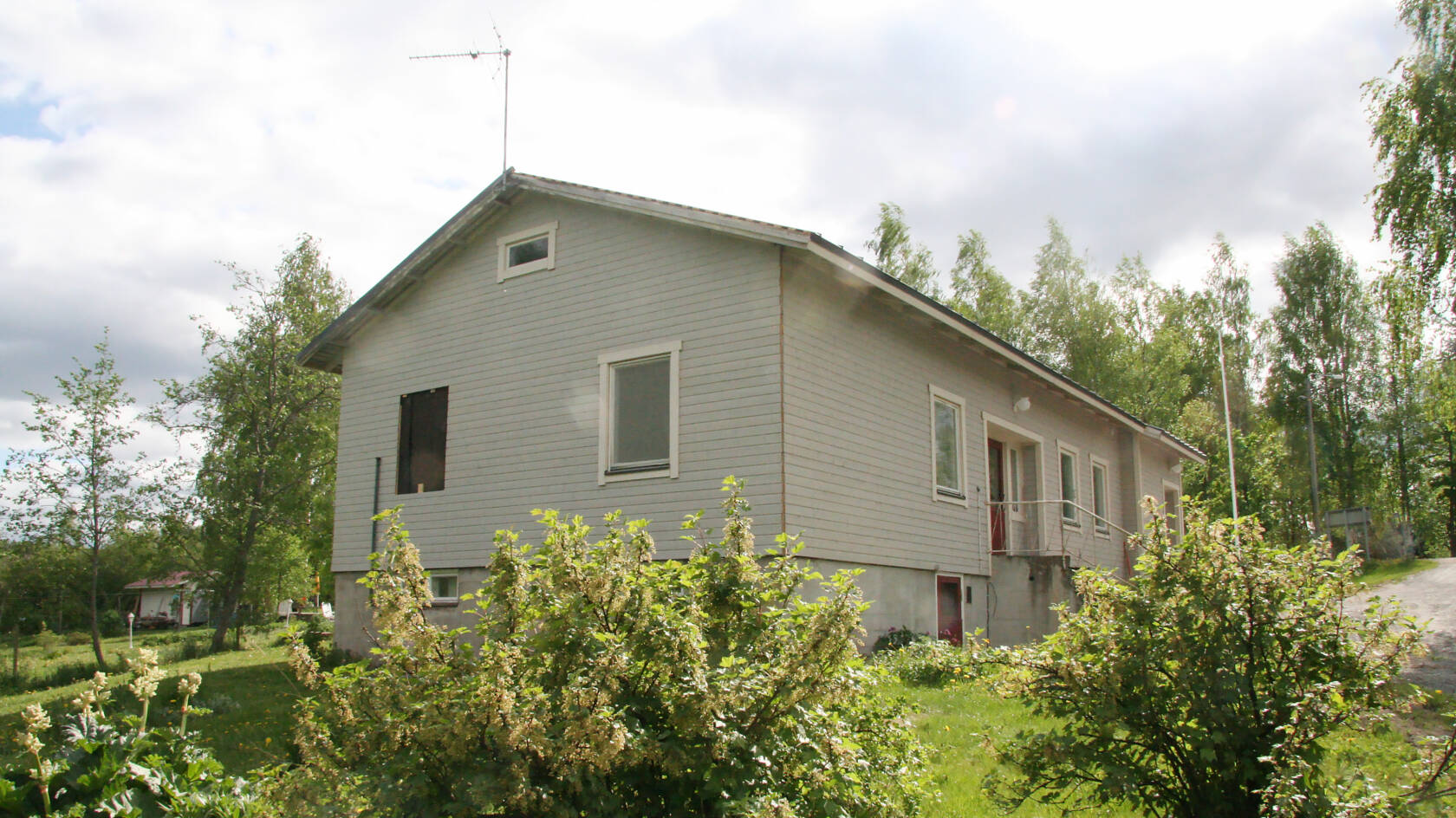 Karhen seurakuntakoti kuvattuna ulkoa marjapensaiden takaa.