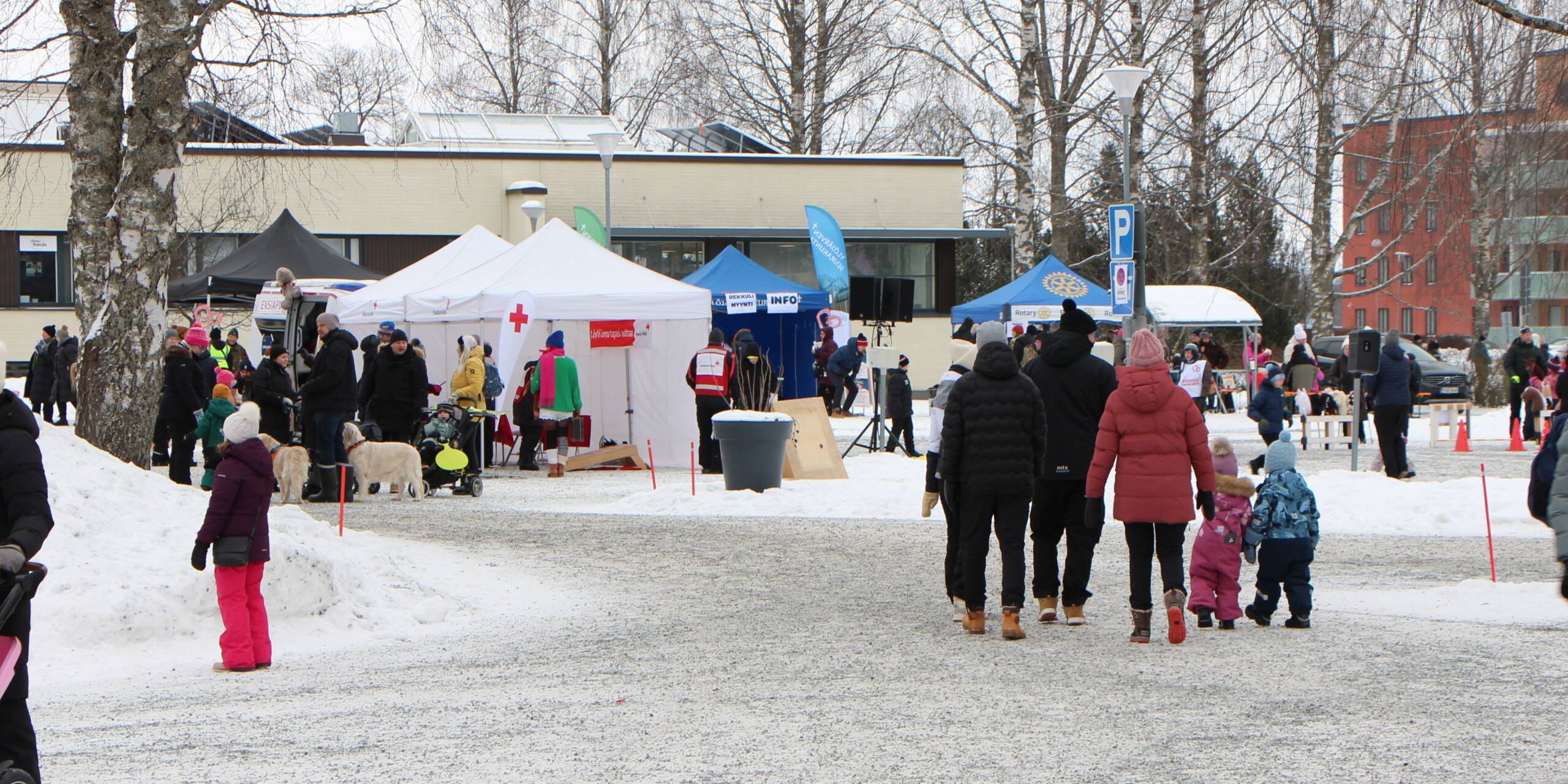 Laskiaistapantuman osallistujia ja jäjestäjien telttoja seurakuntakeskuksen pihalla.