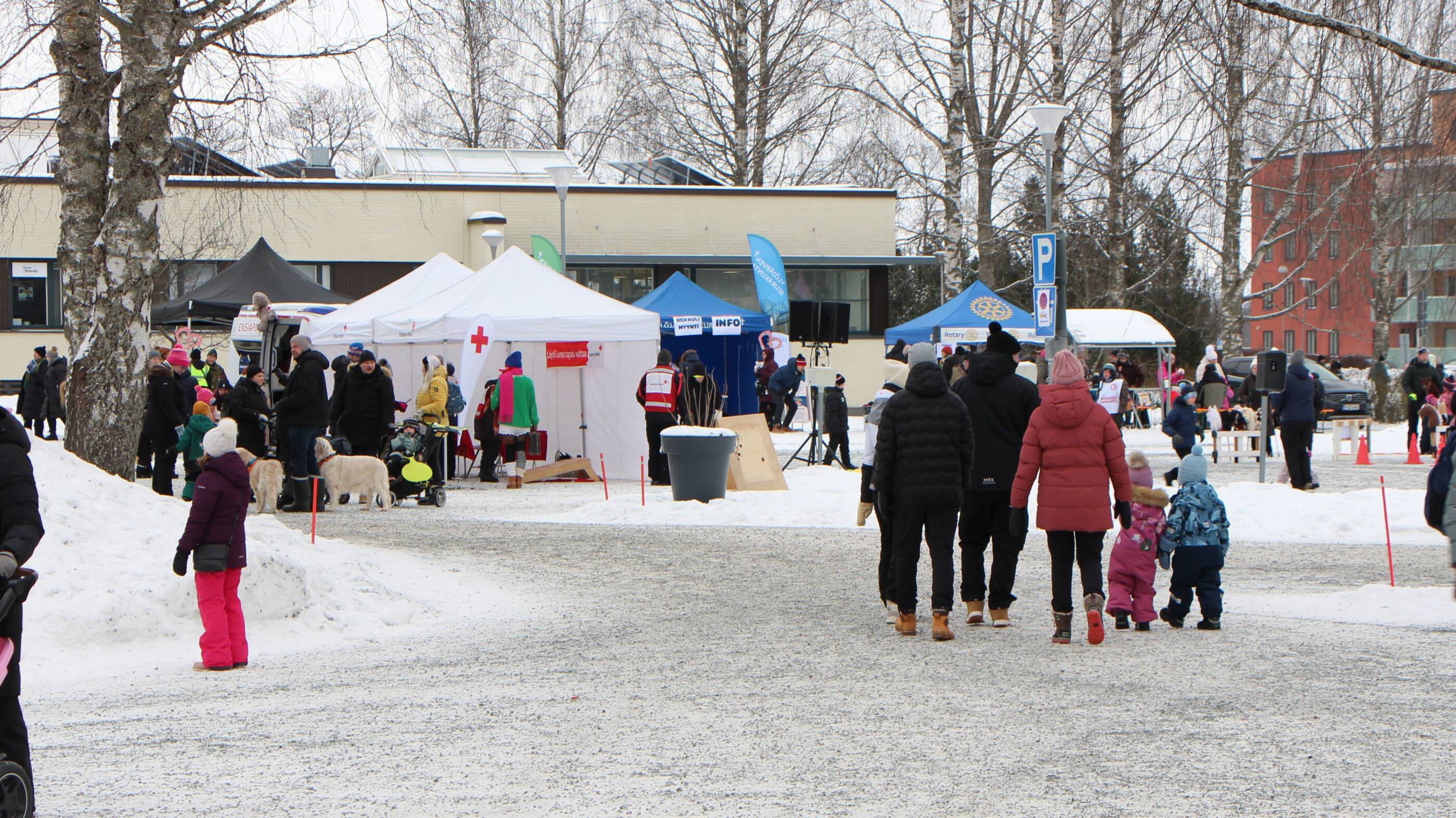 Laskiaistapantuman osallistujia ja jäjestäjien telttoja seurakuntakeskuksen pihalla.
