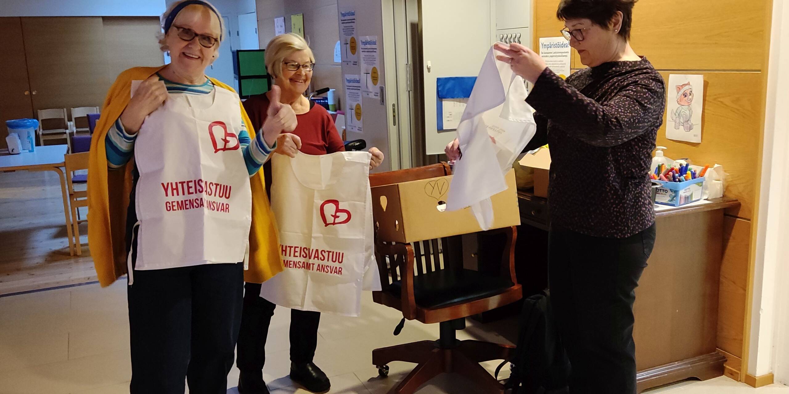 Seurakunnan vapaaehtoiset sovittavat Yhteisvastuukeräyksen tunnusliivejä.