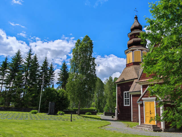 Kurun kirkon kirkkomaata. Puiden takaa siintää kirkon julkisivua.